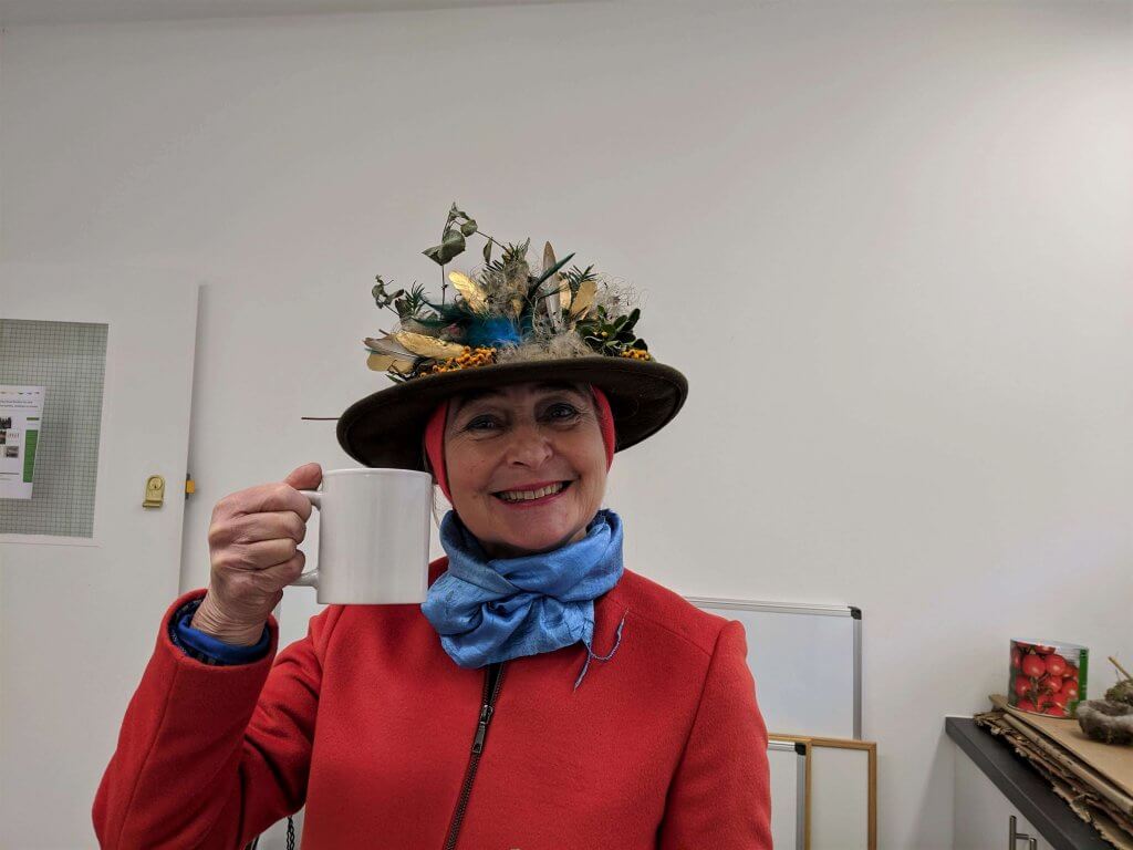 Woman in flowery hat with big smile and a mug of tea